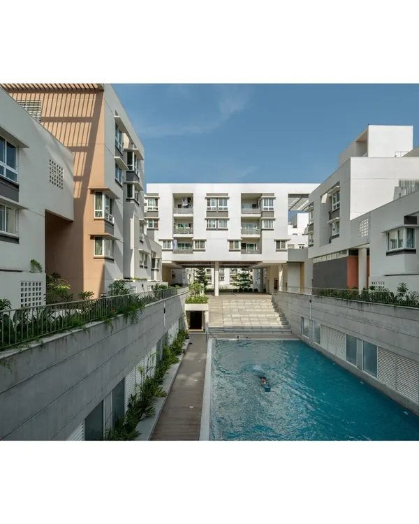 A view of the central swimming pool at Brigade Parkside East, designed as a key community interaction zone. The architecture avoids monolithic forms, instead creating varied blocks and multi-level colonnades that frame the common areas and encourage resident activity.