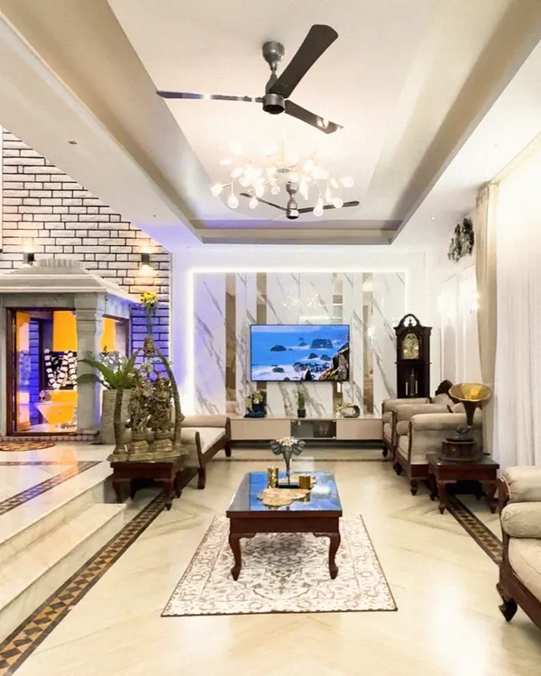 This expansive living room is the heart of the home, designed to be both grand and welcoming. We combined classic wooden furniture with modern elements like a marble-finish TV wall and layered false ceiling with ambient lighting, creating a space that feels both timeless and sophisticated.