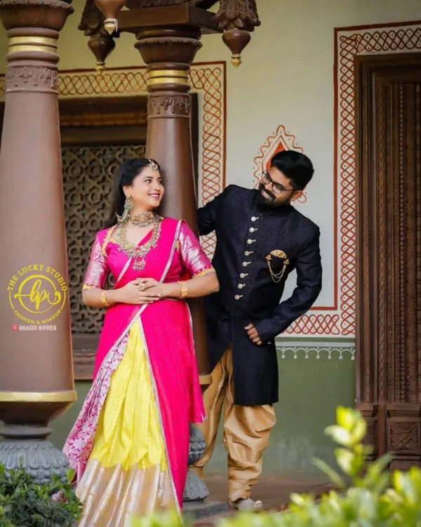 This coordinated set is perfect for a vibrant pre-wedding shoot. It features a bright pink and yellow lehenga paired with a classic navy blue sherwani with gold buttons.