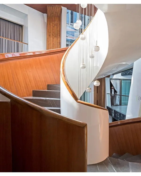 The sculptural staircase of the Cleft House is more than a means of circulation; it's a centerpiece that connects the family across different floors. The flowing form, crafted from wood and white plaster, contrasts with the dark marble and raw concrete textures of the home.