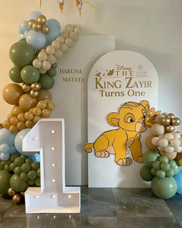 Another take on the Lion King theme for a first birthday. This one features a 'Hakuna Matata' backdrop with a large light-up number '1' and a cute cutout of baby Simba.