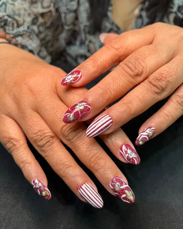 This festive design features a mix of hand-painted candy cane stripes and glittery red nails with bow details. It’s a perfect example of detailed holiday art.