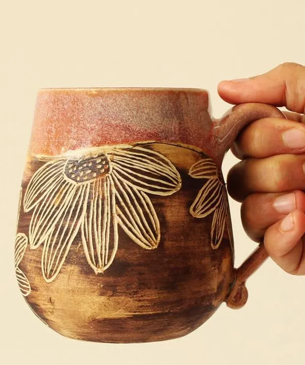The 'Pink Sienna' mug is a study in contrasts, with a glossy pink glaze on top and a rustic, hand-carved floral pattern below. It's a tactile piece that feels wonderful to hold.