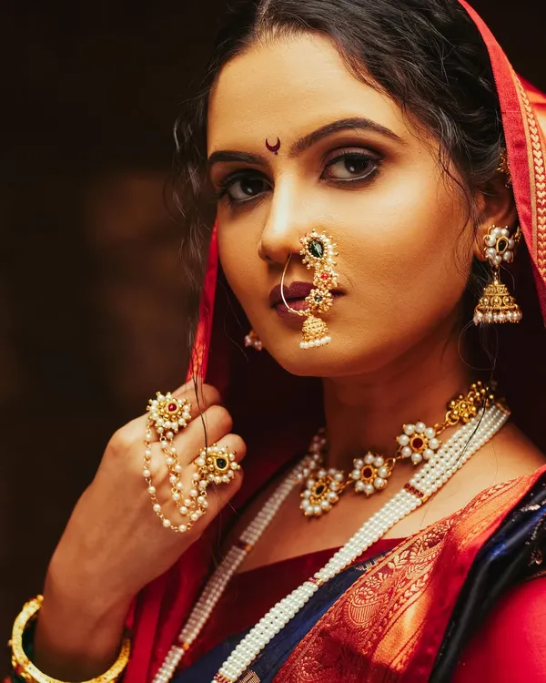 A striking close-up of a model in a traditional Maharashtrian look. This portrait highlights the intricate details of the classic Nath and jewelry, captured with moody studio lighting to create a timeless and powerful image.