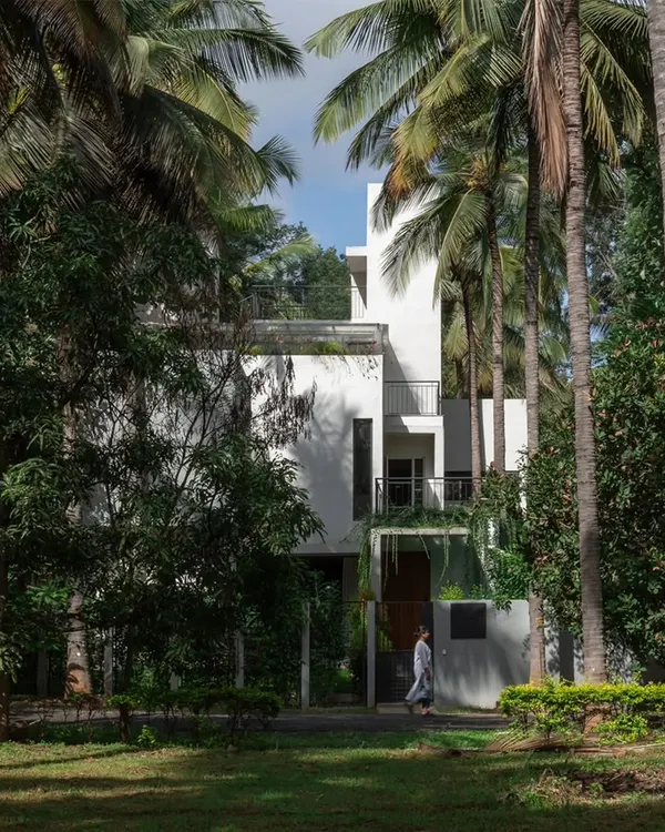 The SANCTUM House, viewed from the surrounding coconut grove. The design's primary goal was to integrate the home into the landscape, preserving existing trees and creating a structure that feels like a natural extension of the orchard.