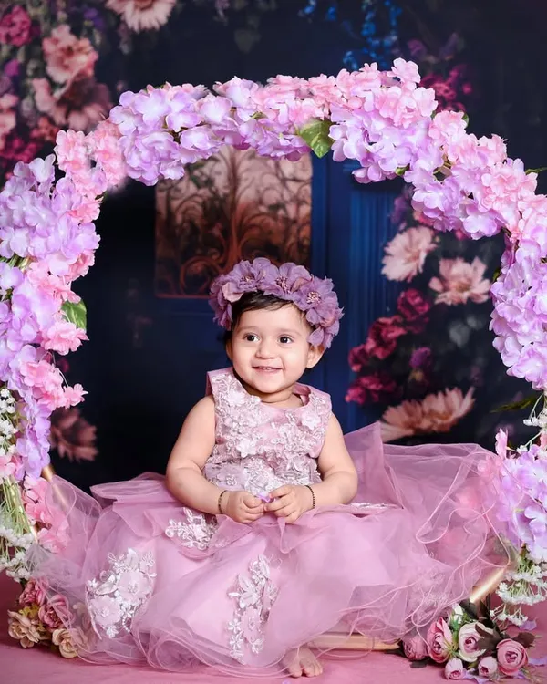 A beautiful baby girl sitting in a floral hoop swing. My studio is filled with enchanting props like this to create dreamy, princess-like portraits for your little one.