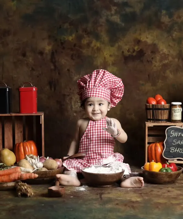 This little chef is ready to cook up some fun in our kitchen-themed setup. Complete with a chef's hat, fresh vegetables, and flour for messy play, it's a recipe for adorable photos.
