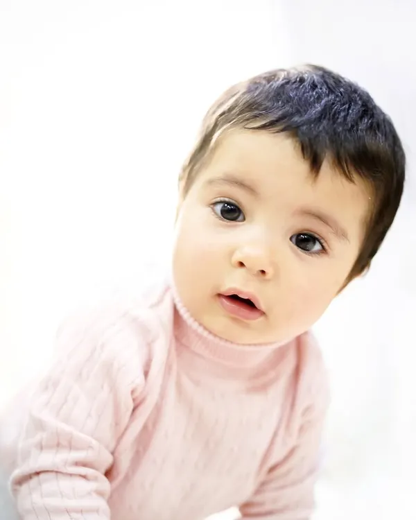 A simple, beautiful portrait of a baby girl at home, captured with soft, natural window light. At-home sessions are perfect for capturing children in their most comfortable and familiar environment.