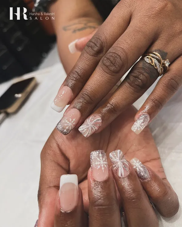A winter wonderland on your fingertips. We created this elegant holiday look with a classic French manicure base and added delicate, hand-painted white snowflakes with a touch of glitter.