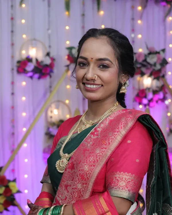 A beautiful Maharashtrian bride ready for her function. The makeup is subtle and glamorous, with a focus on radiant skin and a classic pink lip.