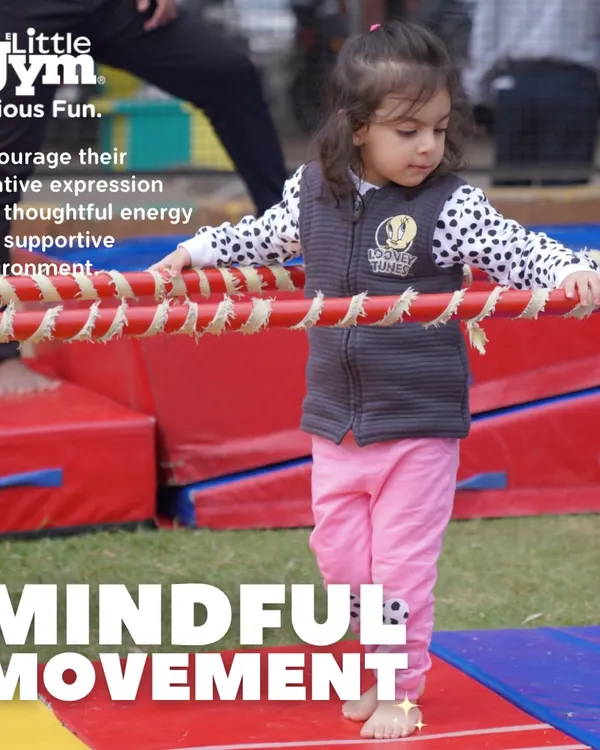 A young girl carefully walks across a rope-covered beam. This activity, part of my 'Mindful Movement' theme, encourages creative expression and thoughtful energy in a supportive environment.