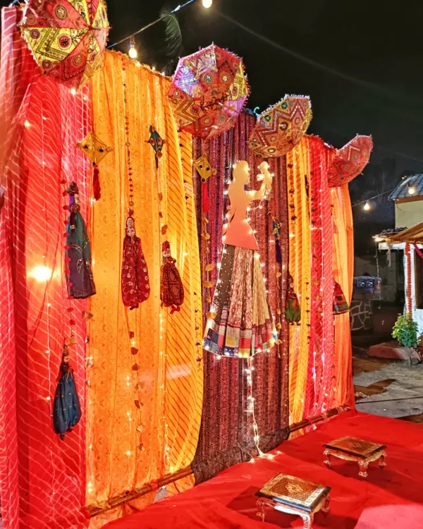 A traditional baby shower (Dohale Jevan) decoration with colorful drapes, Rajasthani puppets, and umbrellas, creating a festive and cultural theme.