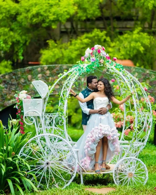 Create a fairytale moment with this whimsical couple's outfit. The high-low gown with floral details and the partner's Nehru jacket are perfect for a romantic shoot with props like this beautiful white carriage.