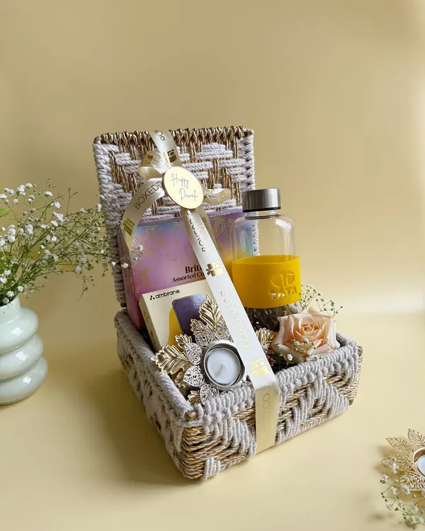 A beautiful corporate Diwali hamper designed for TATA, featuring a custom-branded water bottle, assorted treats, and a festive diya, all packed in an elegant woven basket.