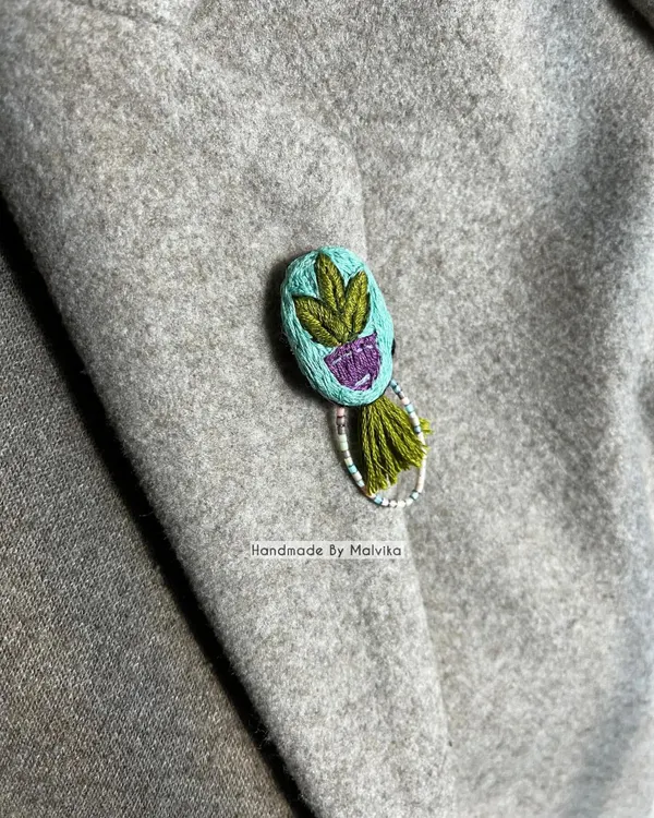 Here is another view of the embroidered plant badge pinned to a coat. I love seeing how a small, handmade accessory can completely change the feel of an outfit, adding a personal and artistic touch.