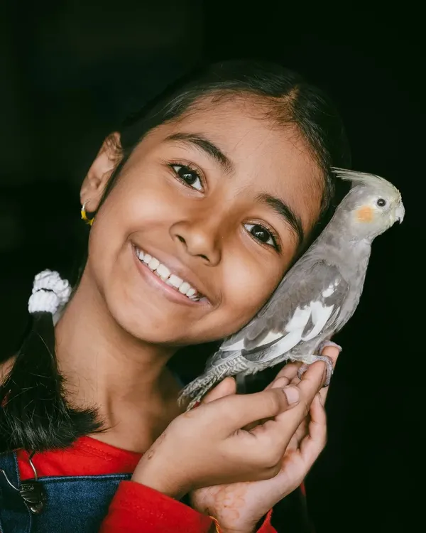 The bond between a child and a pet is truly special. This girl's bright smile as she cuddles her cockatiel is a perfect example of the pure, simple joy I love to photograph.