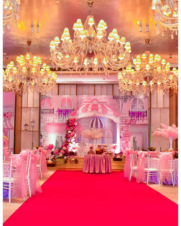 For this Parisian-themed party, I transformed an indoor hall into a romantic street in Paris. The setup includes a grand stage with building facades, a red carpet entrance, and elegant seating under sparkling chandeliers.