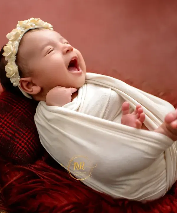 An unposed, beautiful moment of a newborn baby yawning while wrapped snugly in a white swaddle. These are the real, fleeting expressions I love to capture.
