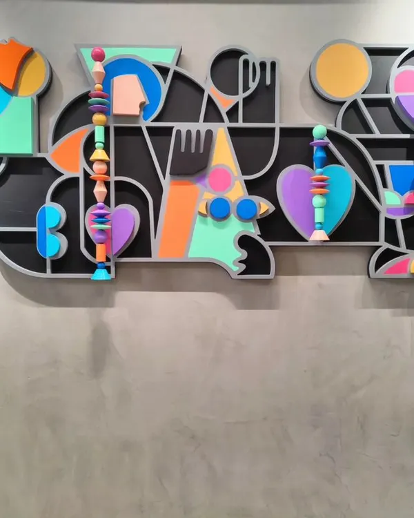 Titled 'Onwards and Upwards', this vibrant mixed-media installation is about personal growth. The piece combines layered MDF, abstract shapes, and hand-painted Channapatna wooden beads to create a colorful, joyful composition that bursts with positive energy.