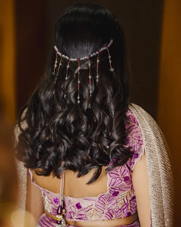 For Surabhi's sangeeth, we created this beautiful half-up, half-down hairstyle with soft waves and a delicate, beaded hair accessory that matched her purple lehenga.
