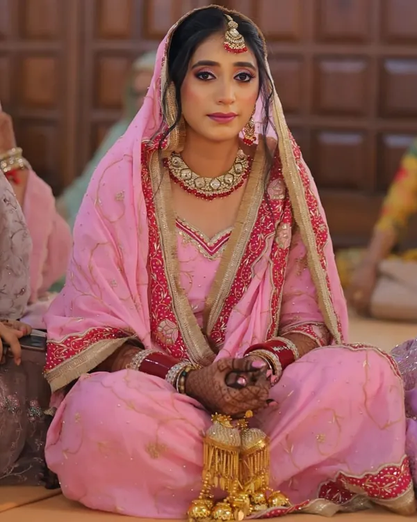 A classic Punjabi bride, radiating grace and serenity. I focused on creating a flawless base with defined eyes and a soft pink lip to complement her beautiful pink wedding suit and traditional jewelry.