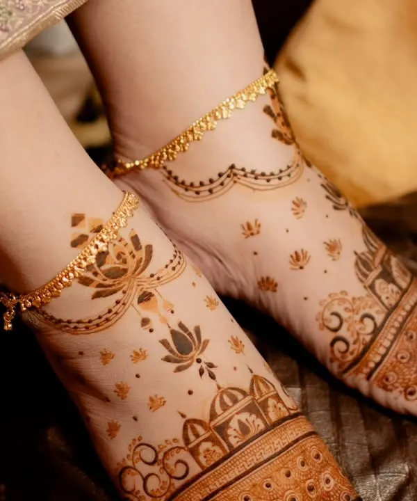 A delicate foot mehendi design that complements the bride's anklets. The pattern features a simple band on the foot with light, scattered motifs extending towards the ankle.