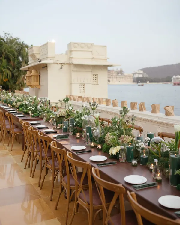 A long, single-table setup for a welcome dinner by the waters of Udaipur. This layout fosters a sense of community and intimacy, allowing guests to connect.
