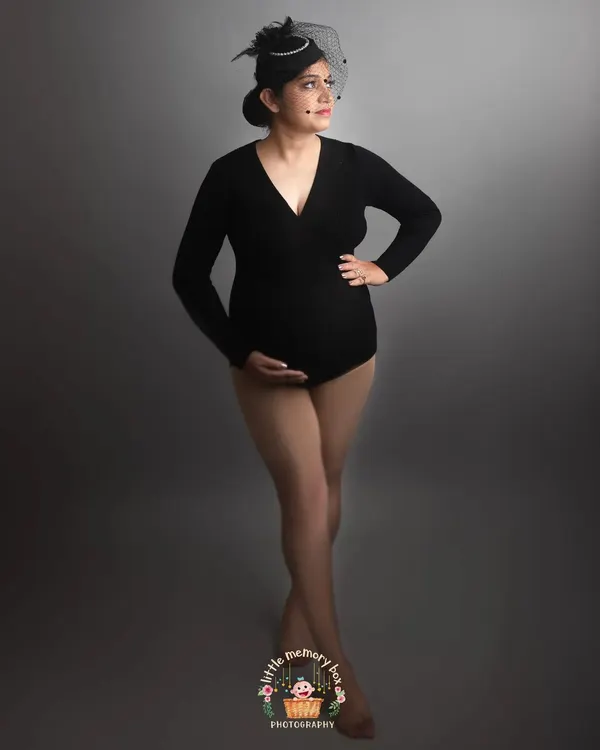 A classic black bodysuit against a simple grey backdrop creates a sophisticated and timeless maternity portrait. This look is all about celebrating the powerful and beautiful shape of your body during pregnancy.