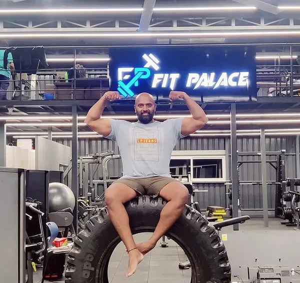Strength and stillness are two sides of the same coin. Here I am at Fit Palace, taking a moment to flex after a powerful workout session, seated on a tractor tire used for functional training.