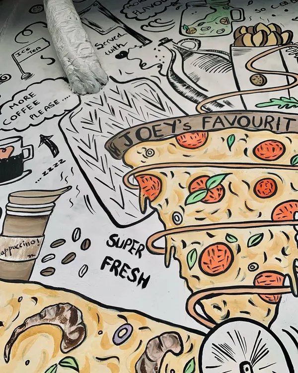 For this pizza cafe's exterior, I illustrated their bestsellers in a quirky doodle style. This section features "Joey's Favourite" pizza, a fun nod for F.R.I.E.N.D.S. fans, with the artwork even wrapping around a pipe.