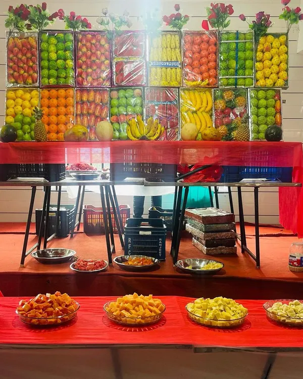 Our grand fruit display table. We create an impressive wall of fresh fruits like apples, oranges, bananas, and pineapples, with cut fruit platters ready for guests to enjoy.