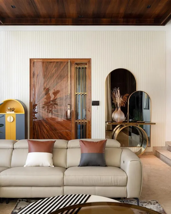 The entrance to the penthouse features a 9-foot veneer door that opens into the voluminous living space. I used a custom brass console table with tinted mirrors against a white grooved panel wall to create a welcoming and luxurious first impression.