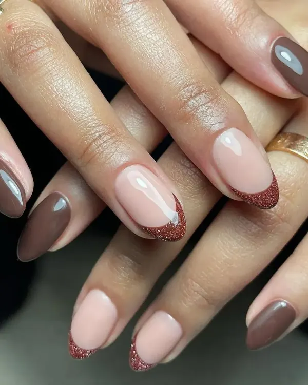 A chic and earthy design combining solid brown nails with a glittery brown French tip on an almond shape.