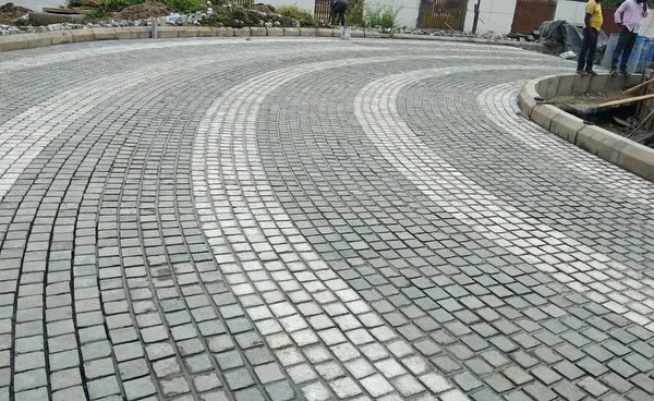 A curved driveway created with grey and white cobblestones. This pattern adds a dynamic and elegant feel to the entrance of the property.
