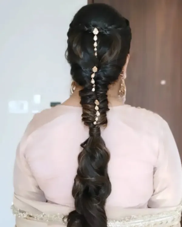 A stunning and intricate pull-through braid, decorated with delicate hair jewelry. This is a modern and stylish choice for a Mehendi or Sangeet event.