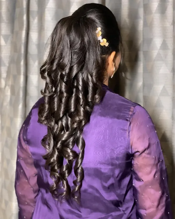 A stunning high ponytail with structured curls. This hairstyle is modern, chic, and keeps the hair off the face, perfect for a party.