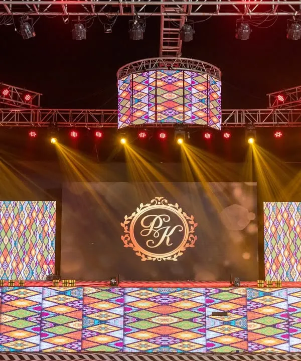 A massive, fully-equipped Sangeet stage with multiple LED screens and a complex lighting rig. I design stages like this to provide a versatile and dynamic backdrop for a variety of performances, complete with custom monograms.