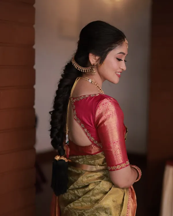 A detailed view of a classic South Indian bridal braid. This hairstyle is neat and elegant, adorned with a traditional earpiece chain (matti) for a complete look.