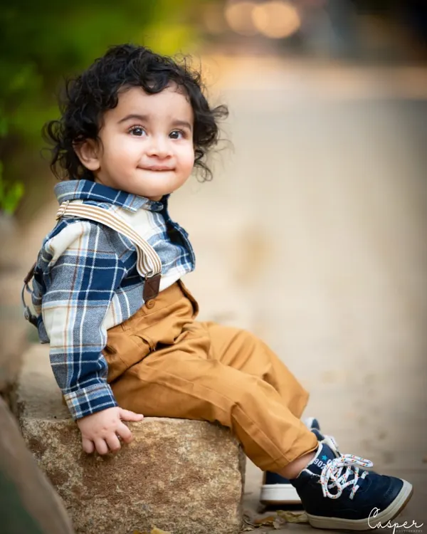 A handsome little man enjoying the outdoors. His plaid shirt and suspenders are perfect for this rustic, natural setting, and his smile is just infectious.