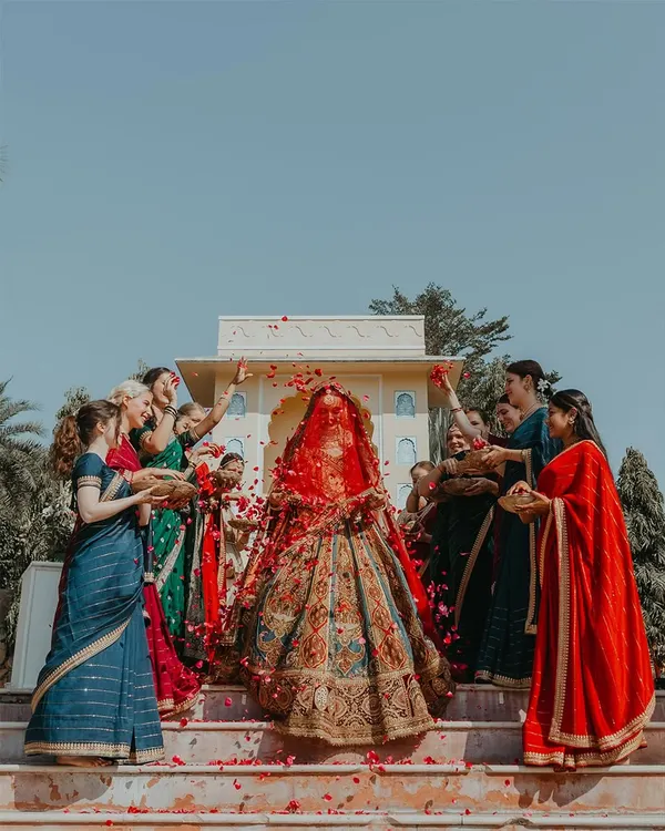 The bride's grand entrance at a beautiful Rajasthan wedding, showered with petals by her bridesmaids. This is a moment of pure celebration and anticipation.