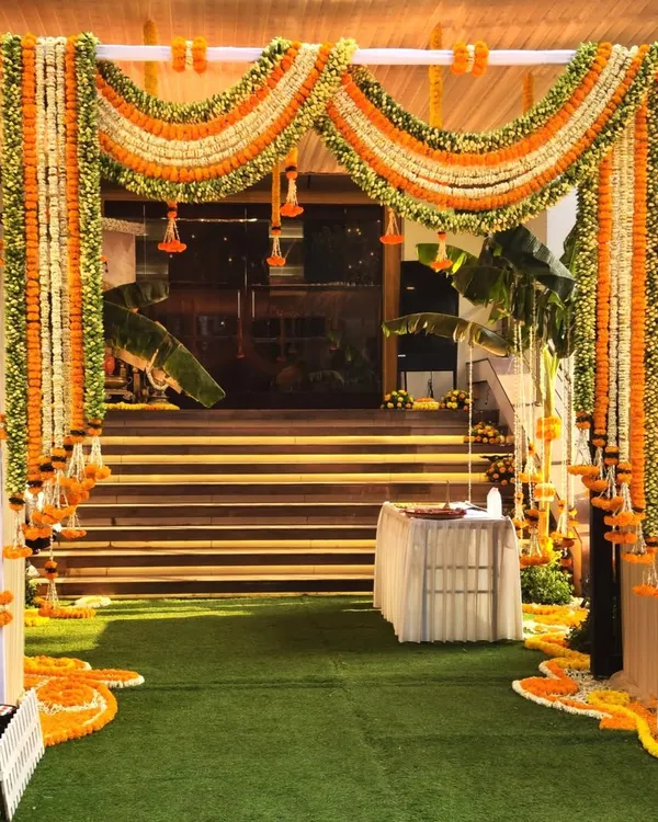 The grand entrance for a Ram-themed thread ceremony at Siddharth Banquets. We used lush garlands of orange and white marigolds to create a traditional and welcoming archway for guests.