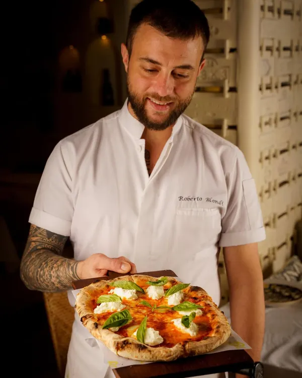 A proud chef presenting his creation. This shot for Bizza Mumbai connects the food to the person who made it, adding a layer of authenticity and passion. The Neapolitan style pizza looks fresh and delicious.