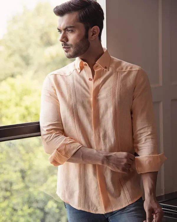Invest in quality, feel the difference. This peach linen shirt, with its subtle pintuck details, is made from the finest materials for lasting comfort and style on warm days.