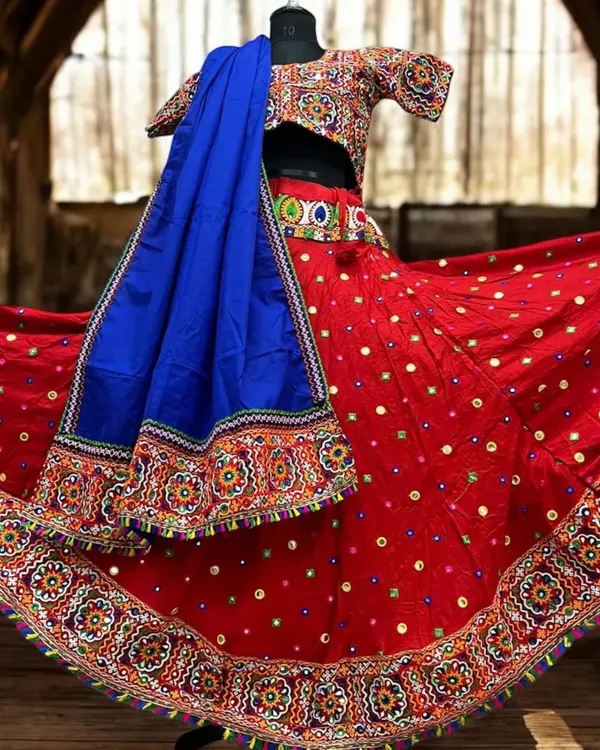 This classic red dandiya lehenga is a showstopper. The skirt and blouse are covered in traditional Kutchi embroidery and mirror work, paired with a contrasting royal blue dupatta for a truly vibrant look.