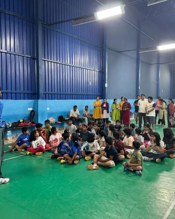A coach leads a group discussion with our summer camp students. We teach court etiquette and game strategy in addition to physical skills, with parents invited to observe.