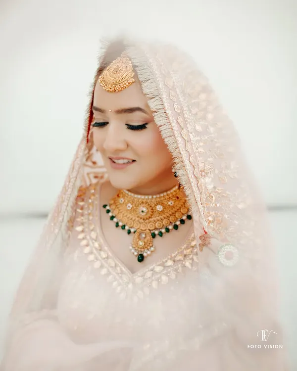 A soft and delicate portrait of a Sikh bride, her eyes gently closed, highlighting her beautiful makeup and traditional gold jewelry.