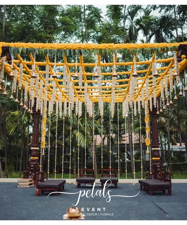 My passion is creating breathtaking mandaps that feel both grand and deeply personal. This design, with its magnificent Kerala-style pillars and a canopy of fresh chrysanthemums, is a perfect example of how I blend architectural elegance with the timeless beauty of traditional flowers and temple bells.