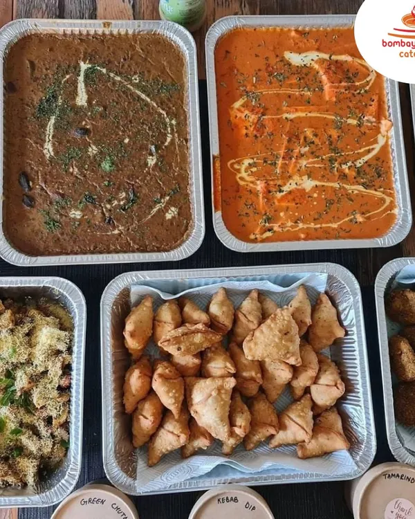 An overhead view of a typical bulk food order, perfect for a party. This spread includes our creamy Dal Makhani, Paneer Butter Masala, mini samosas, and other favorites, delivered in ready-to-serve foil trays.
