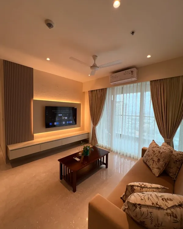 This living room is all about creating a warm and inviting atmosphere. We used soft, neutral tones, textured wall paneling, and ambient backlighting for the TV unit to create a cozy space perfect for relaxing.