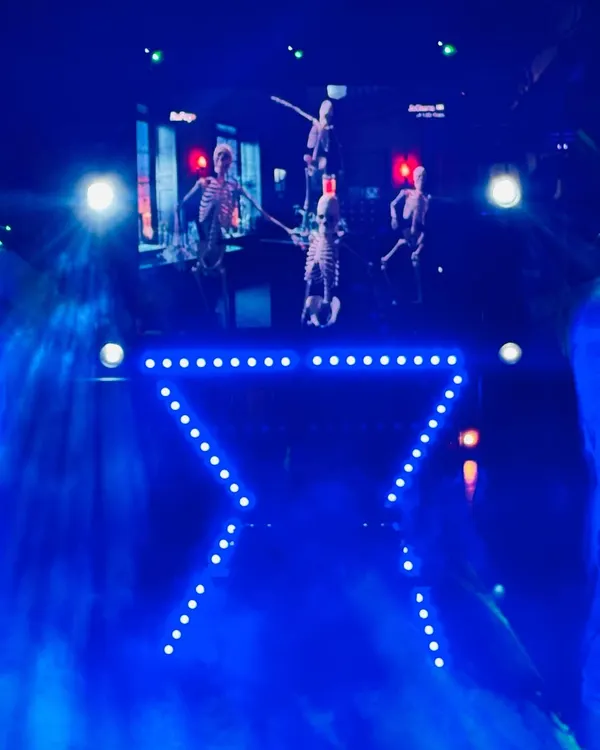 This is my compact DJ setup, perfect for house parties or smaller venues. The package includes sound, a custom X-shaped light truss, and an LED wall, seen here with spooky visuals for a themed party.